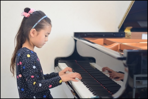 グランドピアノを弾く女の子の画像
