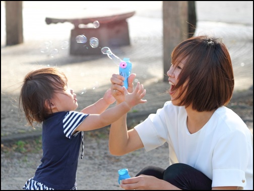 幼児と母親が公園でシャボン玉で遊ぶ画像