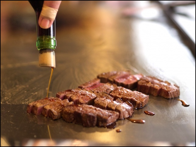 テンダーロインステーキを鉄板で焼きながら味付けしている画像