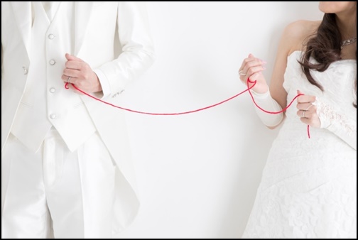 ウエディングドレス姿で赤い糸を繋げている画像